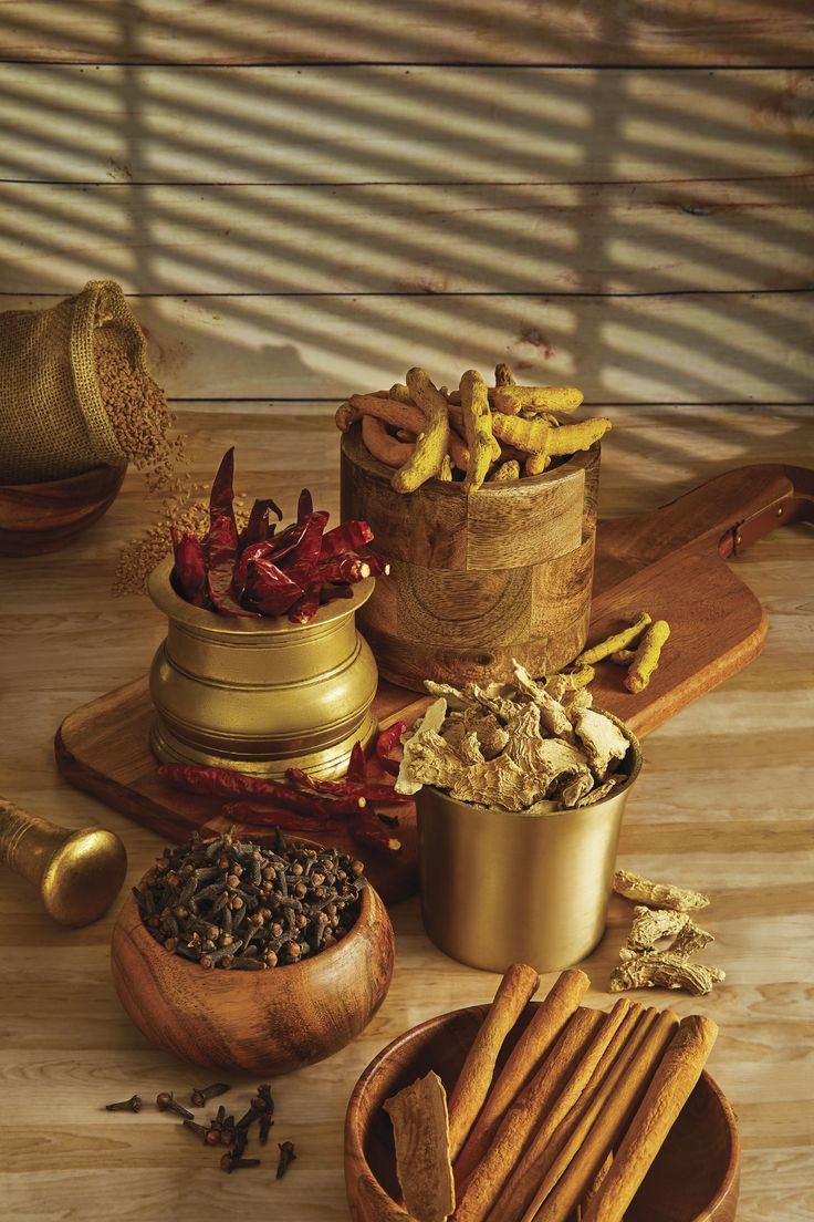 Assortment of warming spices including cinnamon, clove, nutmeg, chilli pepper, and blended powders arranged on a textured surface.