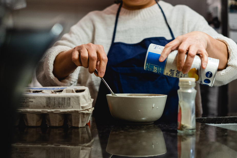 Person stirs a bowl and holds salt to stir